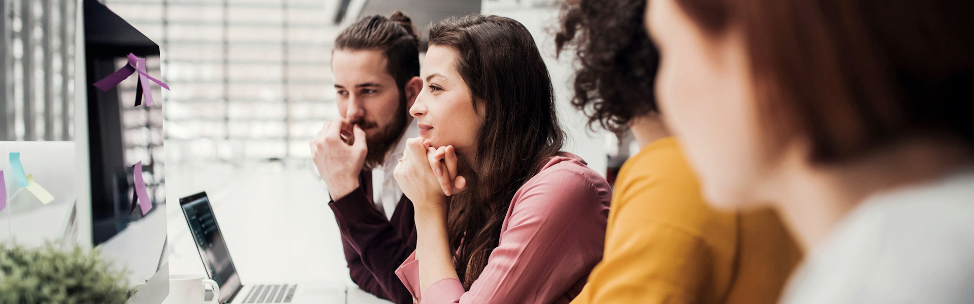 A group of marketing consultants are looking at a monitor reviewing a digital marketing campaign