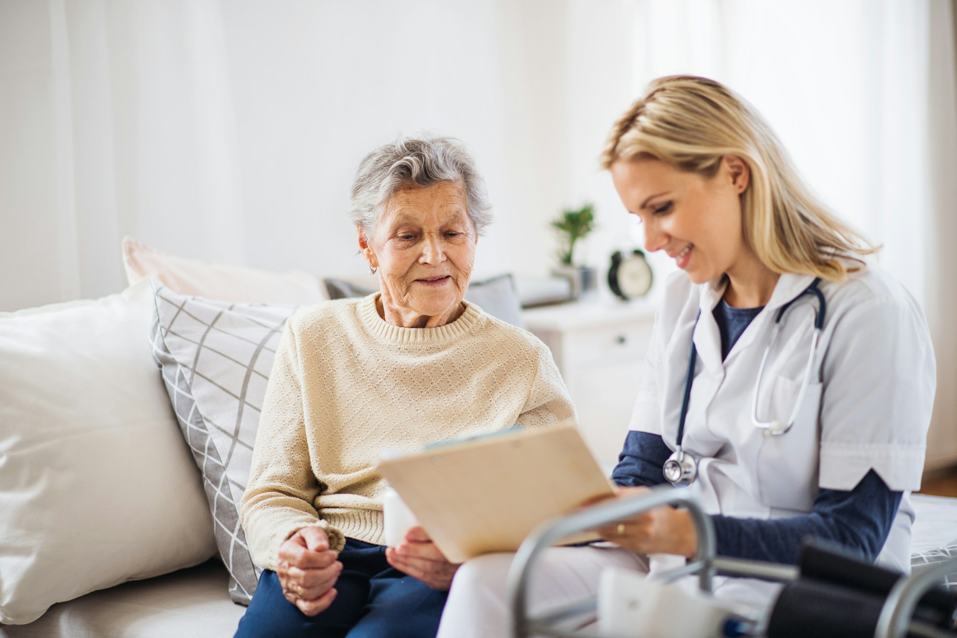 female-doctor-with-female-patient Female doctor reviewing results with an elderly female patient sitting on her bed