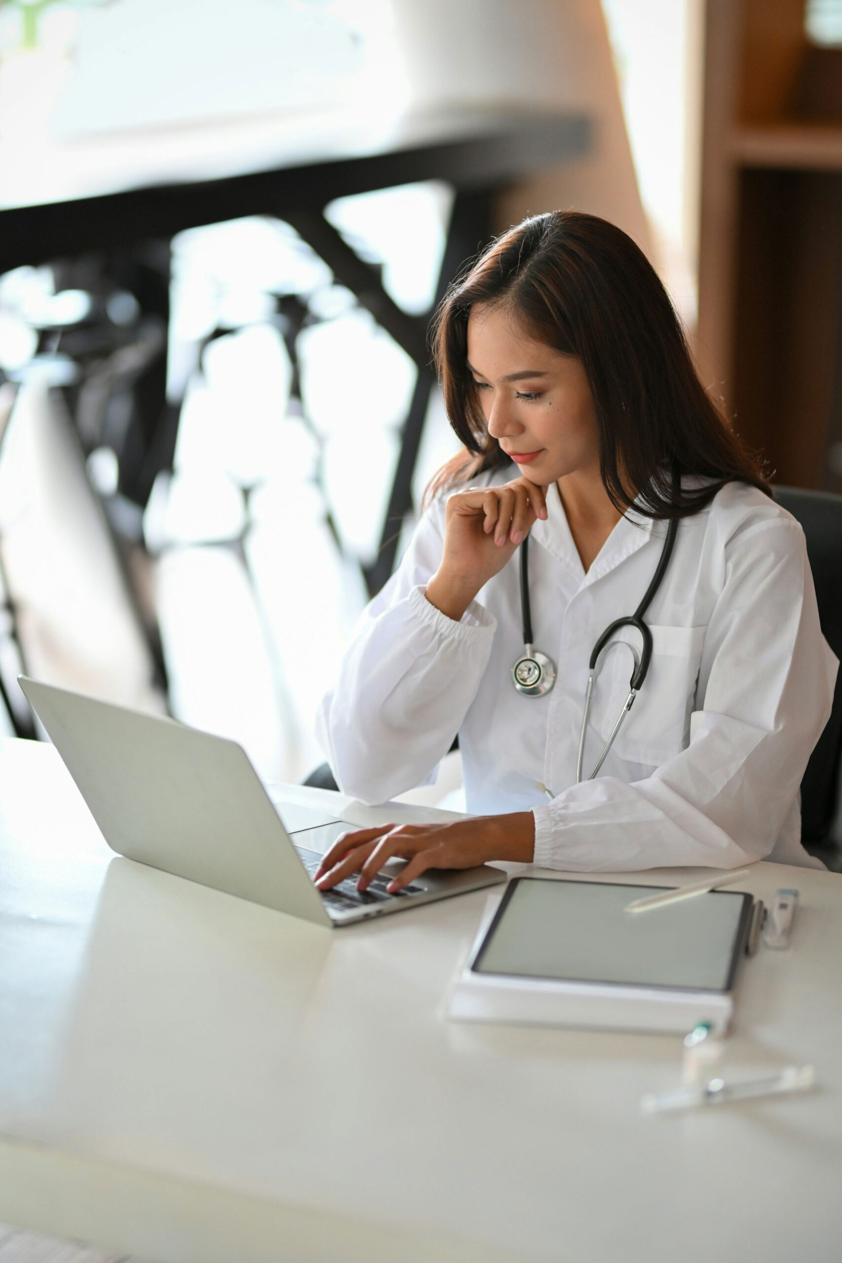 Female doctor sitting at her desk reviewing healthcare website on her laptop